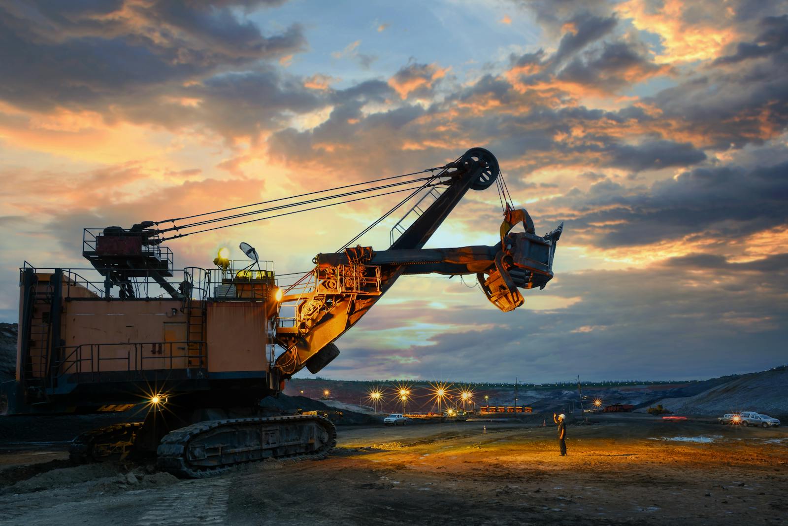 Excavator and crane silhouetted at sunset on a U.S. jobsite